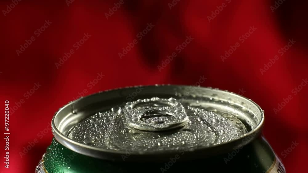 Water droplets on aluminium can of soda or beer. A cold drink rotates on a red cloth background. Water droplets on aluminium can of soda or beer. A cold drink rotates on a red cloth background.