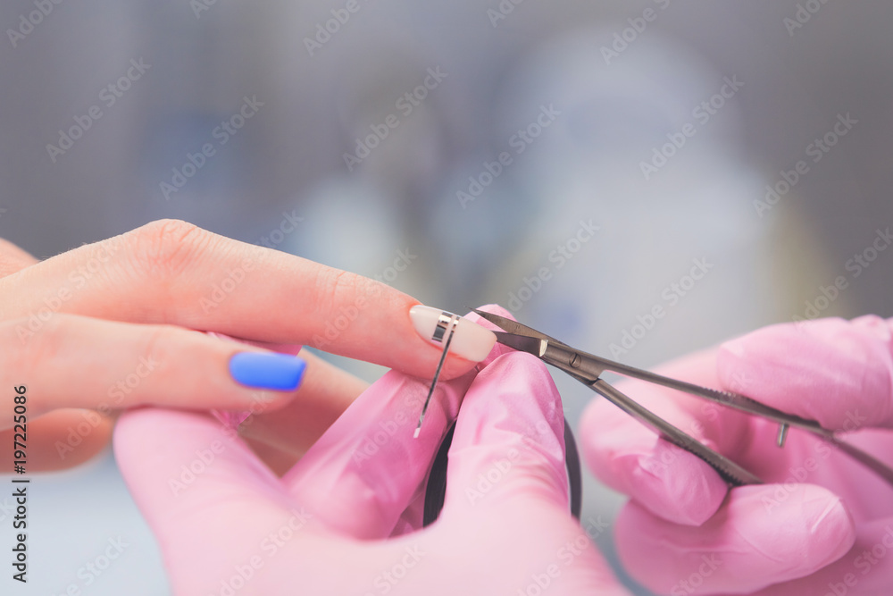 Closeup of manicurist in pink rubber gloves makes decoration on female nails. Professional manicure and nail art in beauty salon Closeup of manicurist in pink rubber gloves makes decoration on female nails. Professional manicure and nail art in beauty salon