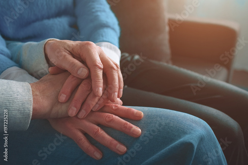 Close up of old people's hands keeping them together. Man has put his hand over her wife's hands. Cut view.