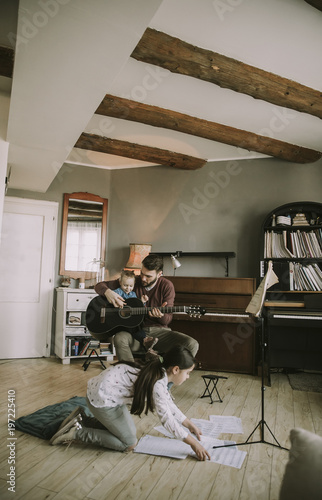 Young father and little daughter playing acoustic guitar