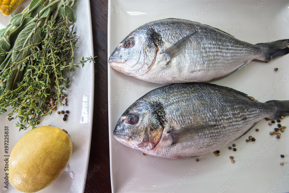 Fresh uncooked dorado with lemon, herbs, oil and spices ready for preparing Fresh uncooked dorado with lemon, herbs, oil and spices ready for preparing