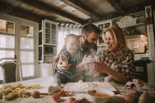 Obraz na plátne Happy family making pasta in the kitchen at home