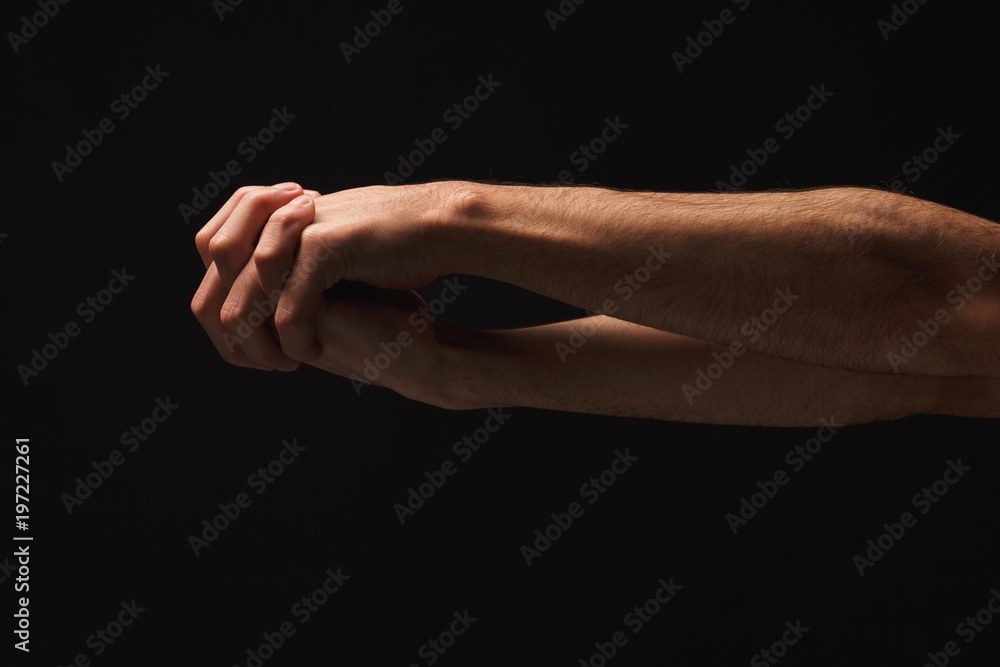 Man holding hands together at black isolated background Man holding hands together at black isolated background