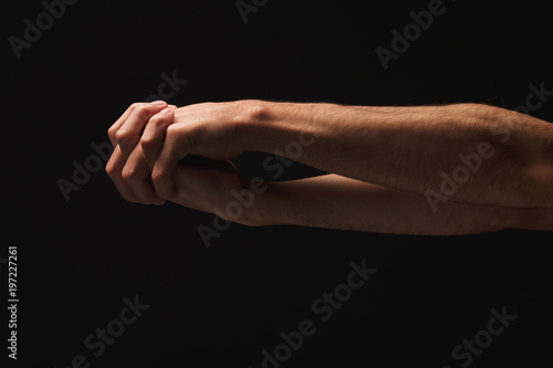 Man holding hands together at black isolated background