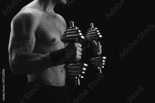 Strong athletic man with dumbbell showes naked muscular body