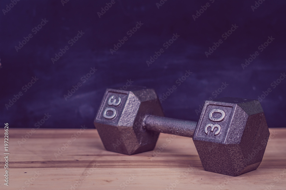 close up of thirty pound dumbbell on wooden floor close up of thirty pound dumbbell on wooden floor