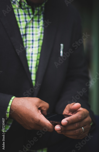 African american man in black suit using mobile device