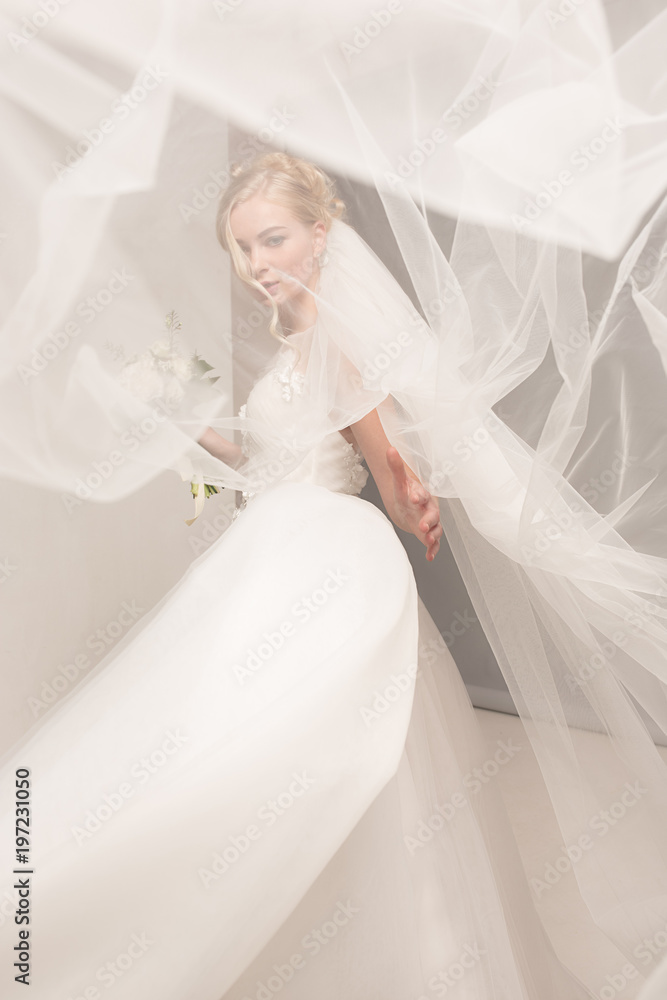 Bride in beautiful dress standing indoors in white studio interior like at home. Trendy wedding style shot. Young attractive caucasian model like a bride tender looking. Bride in beautiful dress standing indoors in white studio interior like at home. Trendy wedding style shot. Young attractive caucasian model like a bride tender looking.