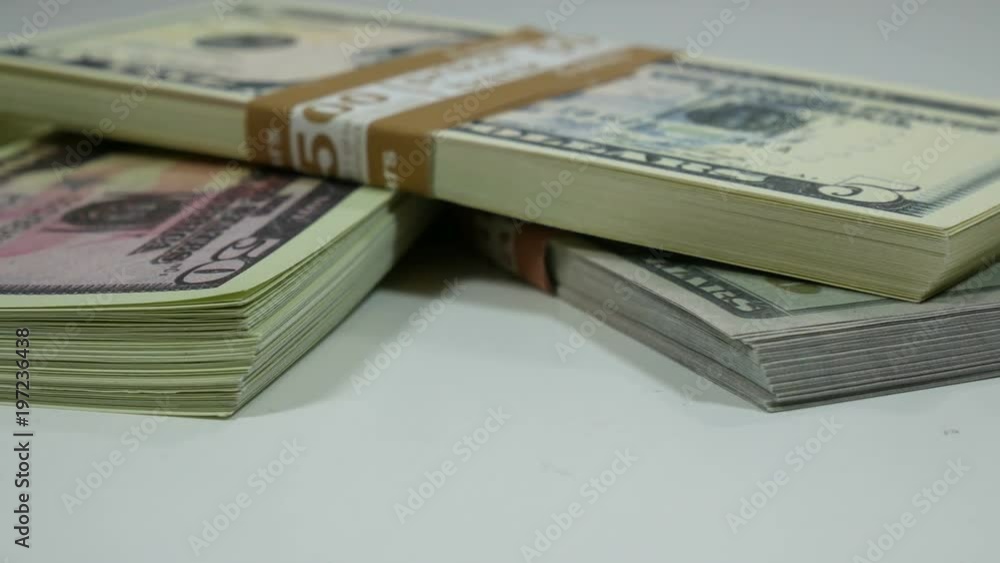 Closeup of a pile of one hundred American dollars cash rotating on the table Closeup of a pile of one hundred American dollars cash rotating on the table