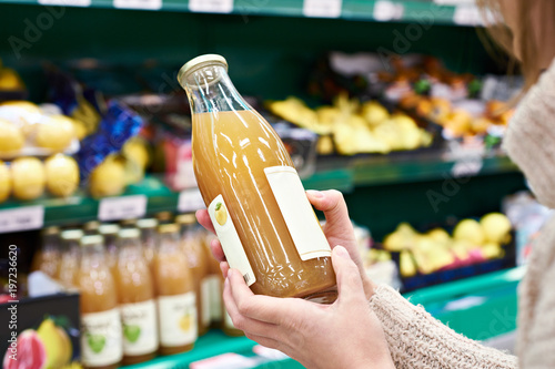Hands with bottle of fresh apple juice in store