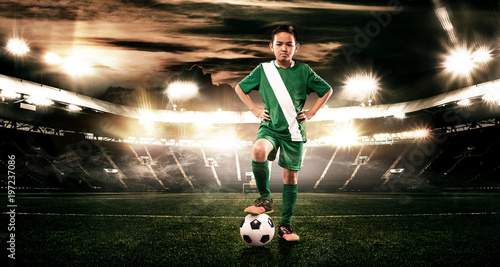 Kid - soccer player. Boy forward in football sportswear on stadium with ball. Sport concept.