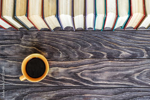 row of books cup with coffee on a wooden background with copy space, top view