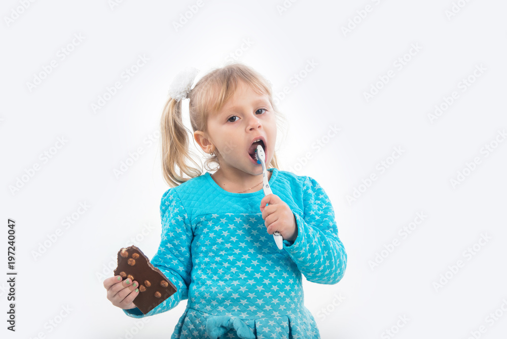 A child, a little girl is holding a toothbrush and a chocolate in her hand, a difficult choice. Diseases of children's teeth and caries. A child, a little girl is holding a toothbrush and a chocolate in her hand, a difficult choice. Diseases of children's teeth and caries.