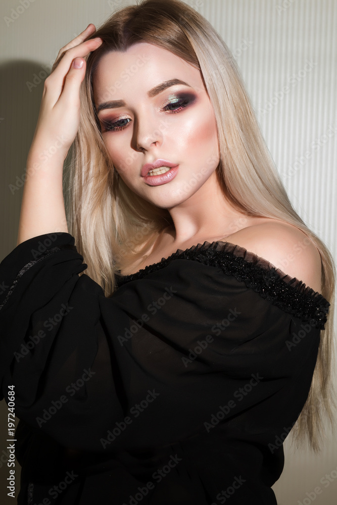 Adorable blonde woman with perfect makeup posing at the white wall Adorable blonde woman with perfect makeup posing at the white wall
