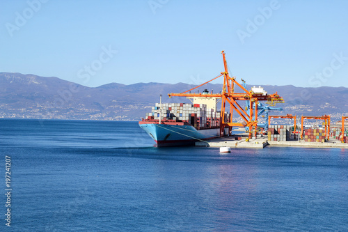 Obraz na plátně Container ship for carriage of goods with containers to shore in port ship port on horizon / Cargo transportation by sea and goods unloading process / Business logistics and transportation concept