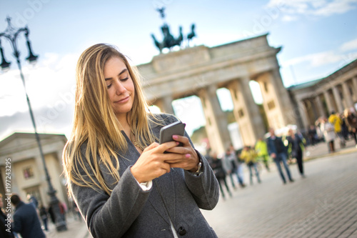 Photography Beautiful girl text messaging while standing near Brandenburg Gate in Berlin, Ge