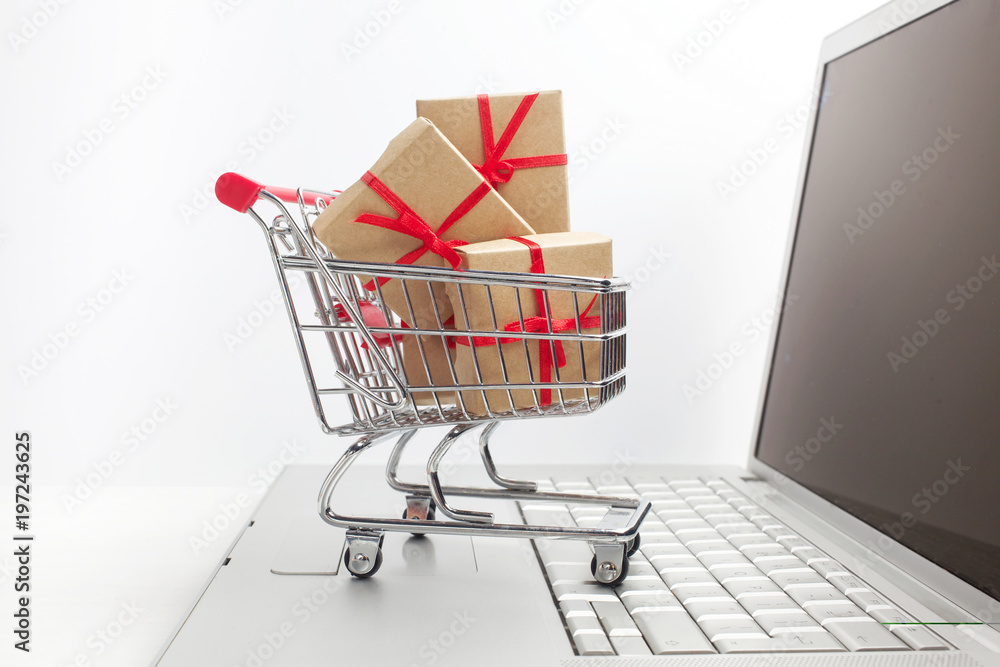 Paper boxes in a shopping cart on a laptop keyboard. Ideas about e-commerce, a transaction of buying or selling goods or services online.