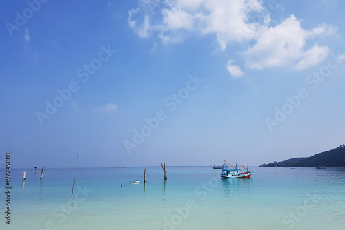 Image of sea coast with hills, boat and cloudy sky