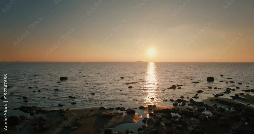 Aerial flight from shore to sea with a view of the ship at sunset