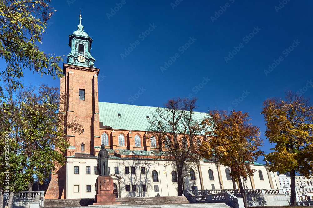 Statue and Gothic cathedral church in autumn in Gniezno .