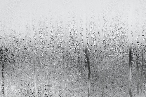 Blue background of natural water condensation, window glass with high air strong humidity, large drops drip. Collecting and streaming down