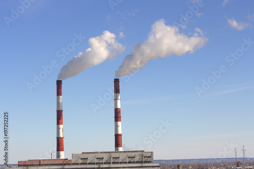 The pipe of the plant emits harmful substances into the atmosphere. Close-up on a sky background