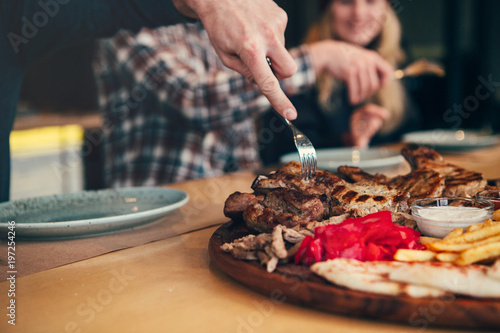 Attractive and happy friens having good time in cafe. They are smiling and eating meat. photo