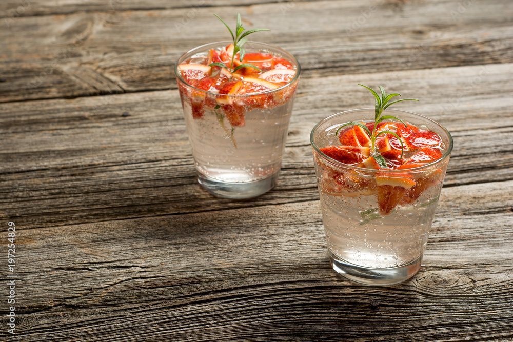 Summer fruit drinks. Fresh lemonade with oranges pieces on rustic wooden background Summer fruit drinks. Fresh lemonade with oranges pieces on rustic wooden background
