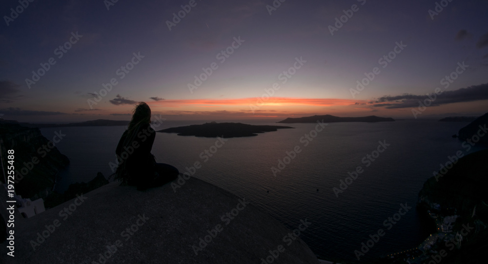 Silueta de una persona diviando y contemplando el atardecer en Santorini Grecia