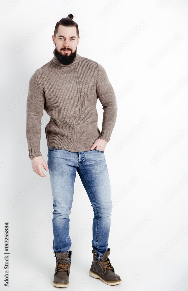 Fashion portrait of young stylish bearded man in trendy casual sweater and  blue jeans and leather boots over white background. Stock-Foto | Adobe Stock