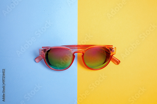 Flat lay fashion set: sunglasses on blue and yellow backgrounds. Fashion summer is coming concept. top view.