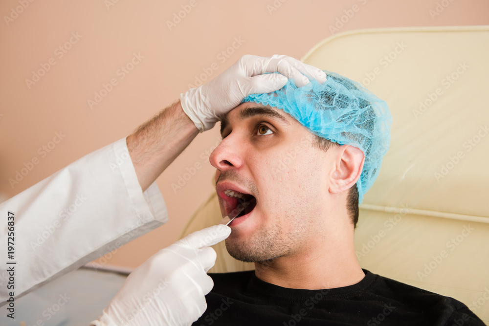 Doctor examining patients mouth with spatula. Doctor examining patients mouth with spatula.