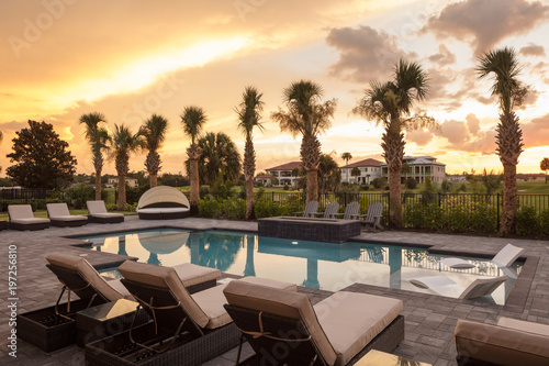 Pool area at sunset overlooking sun loungers and palm trees