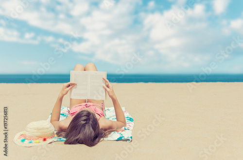 Young woman relaxing reading a book at the beach