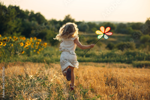 Fototapet Cute little girl playing in the summer field of wheat