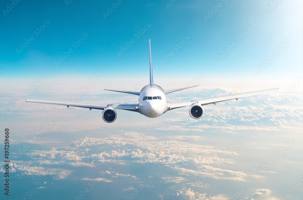 Naklejka premium Samolot pasażerski lecący na poziomie lotu wysoko na niebie ponad chmurami i błękitnym niebem. Zobacz dokładnie z przodu.