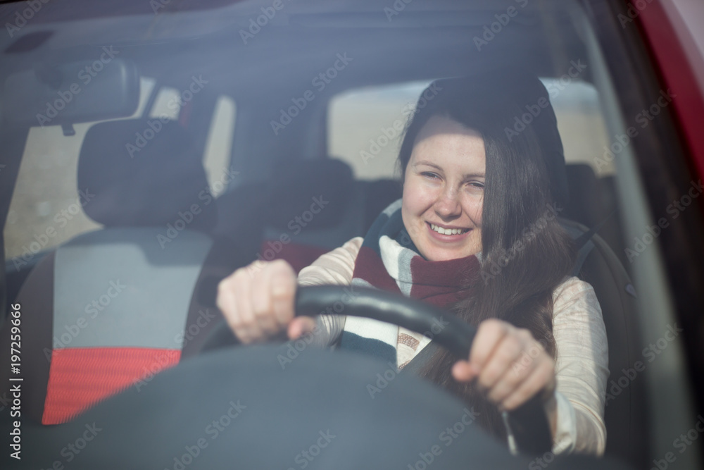 Pretty young brunette woman putting on the safety car seat belt, transportation concept
