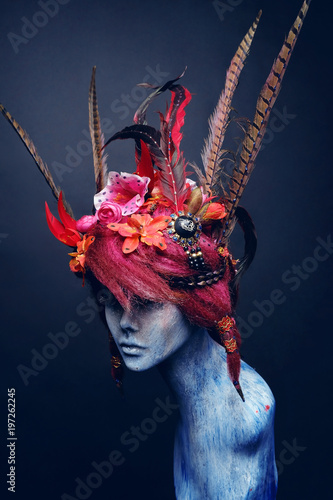 Obraz na plátně Mannequin in creative headwear with flowers and feathers against dark background