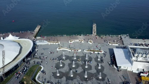 people walk near the fountain and the sea photo