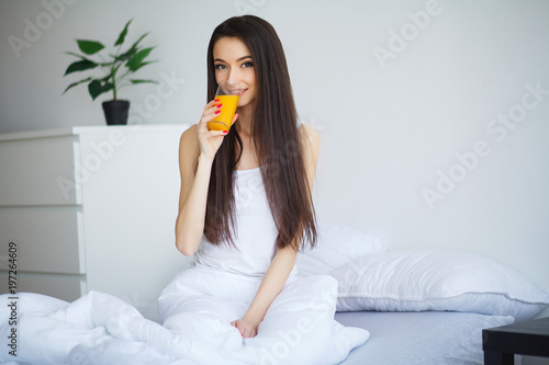 Casual smiling woman holding a glass of orange juice