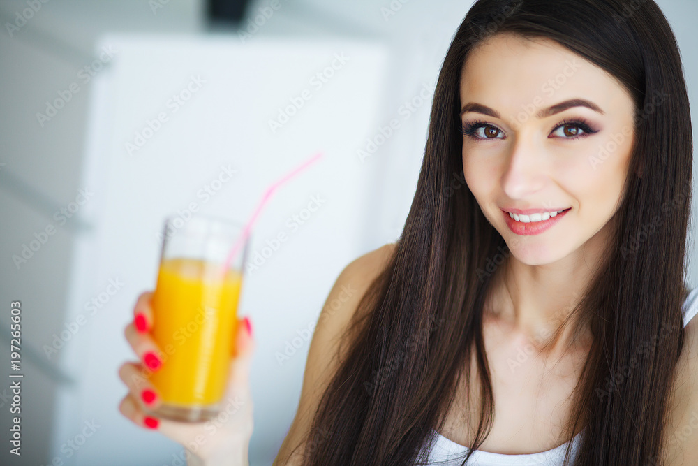 Young woman enjoying a glass of orange juice in the morning as she relaxes sitting on her bed in a healthy diet concept Young woman enjoying a glass of orange juice in the morning as she relaxes sitting on her bed in a healthy diet concept