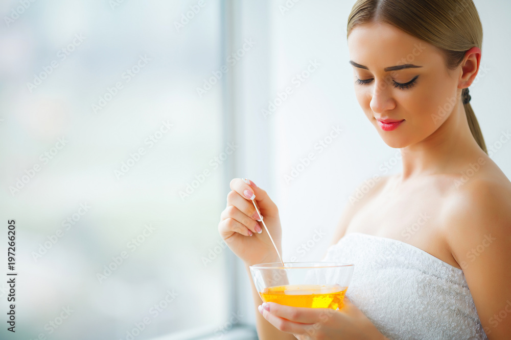 Women hold orange paraffin wax bowl. Woman in beauty salon Women hold orange paraffin wax bowl. Woman in beauty salon