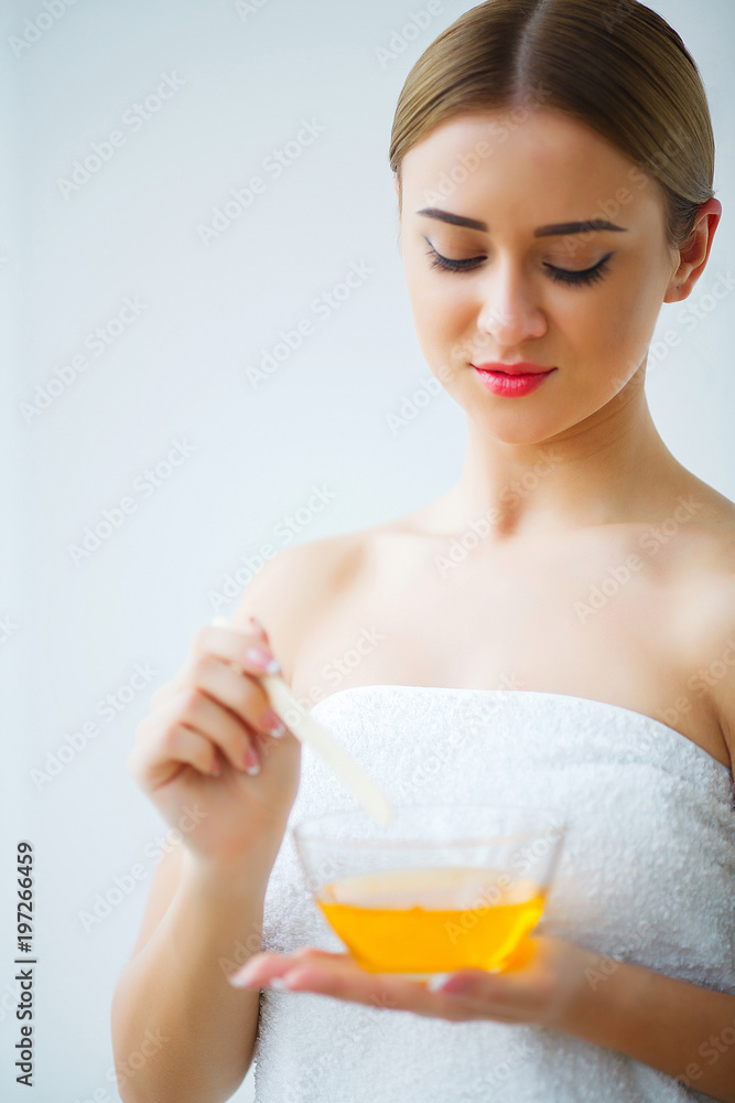 Women hold orange paraffin wax bowl. Woman in beauty salon Women hold orange paraffin wax bowl. Woman in beauty salon