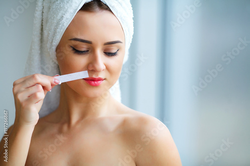 Young beautiful woman makes wax eyelids in her bathroom.
