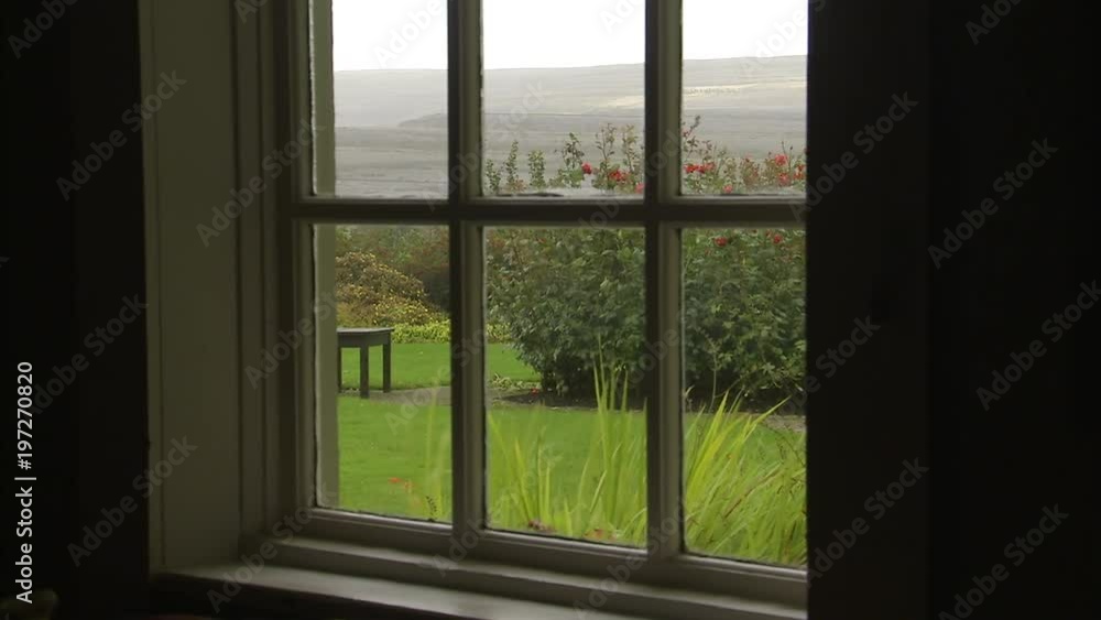 View of a beautiful garden, with grass and flowers, and green hills in the background, all thought an old home window. View of a beautiful garden, with grass and flowers, and green hills in the background, all thought an old home window.