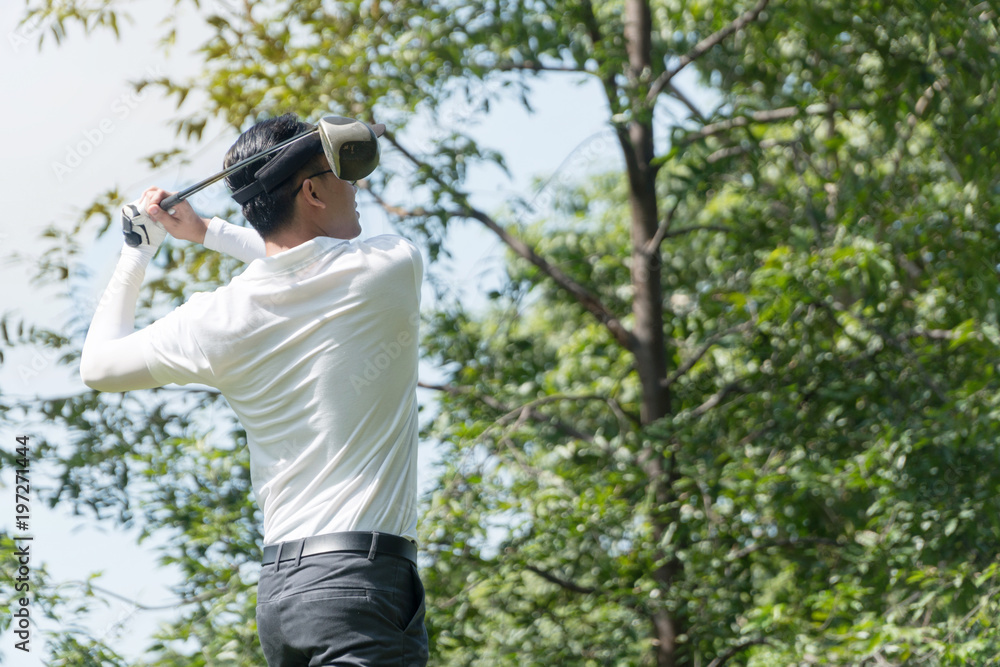 The back of golf Player in white shirt swinging glof. Young man practicing his swing on the golf course. The back of golf Player in white shirt swinging glof. Young man practicing his swing on the golf course.