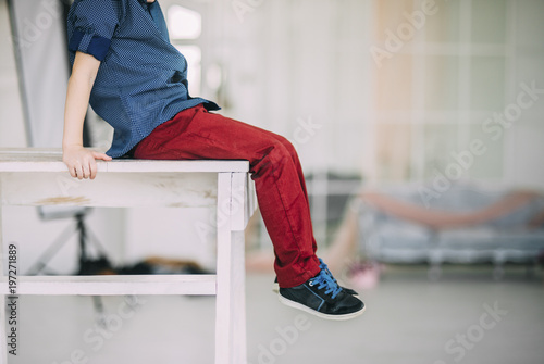 small boy is sitting on the wooden chair in the room