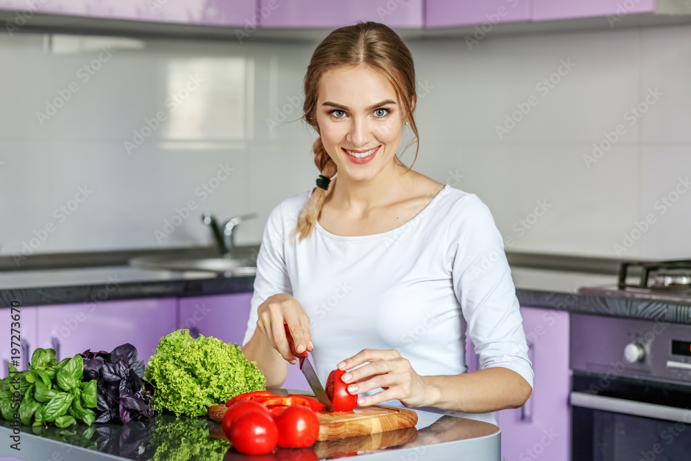 Young happy woman is preparing a good breakfast in the kitchen. Vegetarian. The concept is healthy food, diet, vegetarianism, weight loss. Young happy woman is preparing a good breakfast in the kitchen. Vegetarian. The concept is healthy food, diet, vegetarianism, weight loss.