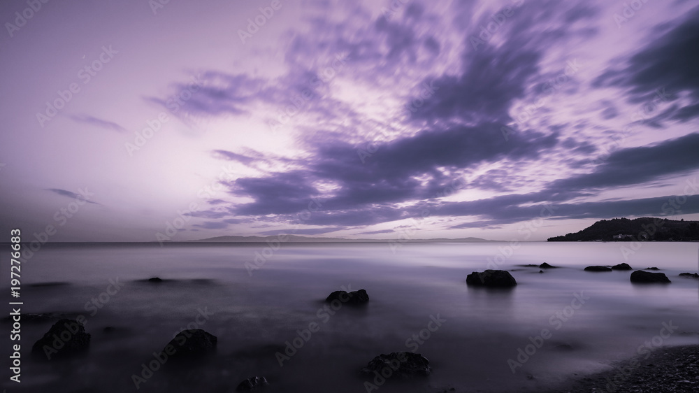 Obraz premium Landscape of sand and rocky shore. Beautiful cloudy seascape at sunset and blurred motion water, Kassandra, Greece.