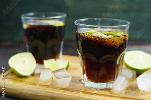 Rum and cola Cuba Libre alcohol cocktail. Refreshing iced longdrink with lime served on wooden board